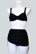 Care Design Athen black bikini bottoms with skirt for women with stoma, featuring a discreet inner pocket and adjustable side ties.